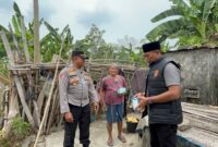 Kapolsek Buay Madang Timur Iptu Swisspo, didampingi Kanit IK Aiptu Dahrul Hutni menyerahkan paket bantuan makanan langsung kepada warga lansia di Desa Tambak Boyo, Kecamatan BMT, Kabupaten OKU Timur.