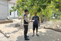 Personel Polsek Buay Madang Timur, Aipda Zulkifli, menyerahkan paket makanan siap saji secara langsung kepada seorang warga di Desa Kedu, Kecamatan Buay Madang Timur, Kabupaten OKU Timur.