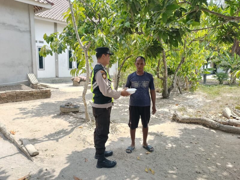 Personel Polsek Buay Madang Timur, Aipda Zulkifli, menyerahkan paket makanan siap saji secara langsung kepada seorang warga di Desa Kedu, Kecamatan Buay Madang Timur, Kabupaten OKU Timur.