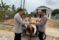 Personel Polsek Buat Madang Timur membagikan masker dan paket bantuan kepada pelajar yang melintas saat menggelar kegiatan sedekah dan berbagi di kawasan Desa Srikaton, Kecamatan Buay Madang Timur, Kabupaten OKU Timur.