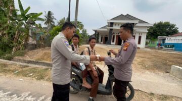 Personel Polsek Buat Madang Timur membagikan masker dan paket bantuan kepada pelajar yang melintas saat menggelar kegiatan sedekah dan berbagi di kawasan Desa Srikaton, Kecamatan Buay Madang Timur, Kabupaten OKU Timur.