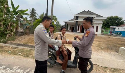 Personel Polsek Buat Madang Timur membagikan masker dan paket bantuan kepada pelajar yang melintas saat menggelar kegiatan sedekah dan berbagi di kawasan Desa Srikaton, Kecamatan Buay Madang Timur, Kabupaten OKU Timur.