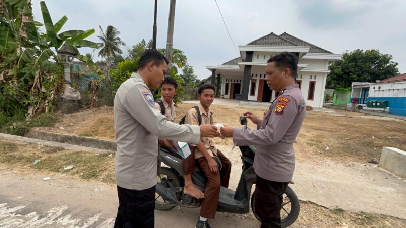 Personel Polsek Buat Madang Timur membagikan masker dan paket bantuan kepada pelajar yang melintas saat menggelar kegiatan sedekah dan berbagi di kawasan Desa Srikaton, Kecamatan Buay Madang Timur, Kabupaten OKU Timur.