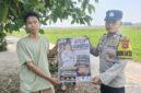 Anggota Bhabinkamtibmas Polsek Buay Madang Timur, Brigadir Tedy Heryadi, menunjukkan pamflet maklumat 