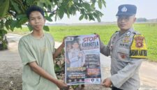 Anggota Bhabinkamtibmas Polsek Buay Madang Timur, Brigadir Tedy Heryadi, menunjukkan pamflet maklumat 