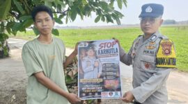 Anggota Bhabinkamtibmas Polsek Buay Madang Timur, Brigadir Tedy Heryadi, menunjukkan pamflet maklumat 
