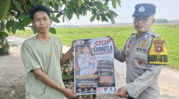 Anggota Bhabinkamtibmas Polsek Buay Madang Timur, Brigadir Tedy Heryadi, menunjukkan pamflet maklumat 