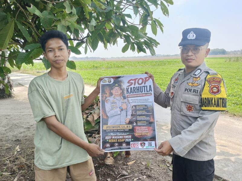Anggota Bhabinkamtibmas Polsek Buay Madang Timur, Brigadir Tedy Heryadi, menunjukkan pamflet maklumat 
