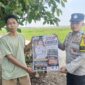 Anggota Bhabinkamtibmas Polsek Buay Madang Timur, Brigadir Tedy Heryadi, menunjukkan pamflet maklumat 