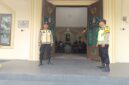 Personel Polsek Buay Madang Timur, Aipda Khoirul Alkaf dan Bripka Nur Kholik, bersiaga di depan pintu masuk Gereja Trinitas Bangun Sari BK 3, Kecamatan Buay Madang Timur, Kabupaten OKU Timur, Sumatera Selatan.