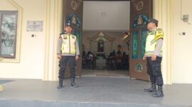 Personel Polsek Buay Madang Timur, Aipda Khoirul Alkaf dan Bripka Nur Kholik, bersiaga di depan pintu masuk Gereja Trinitas Bangun Sari BK 3, Kecamatan Buay Madang Timur, Kabupaten OKU Timur, Sumatera Selatan.