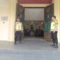 Personel Polsek Buay Madang Timur, Aipda Khoirul Alkaf dan Bripka Nur Kholik, bersiaga di depan pintu masuk Gereja Trinitas Bangun Sari BK 3, Kecamatan Buay Madang Timur, Kabupaten OKU Timur, Sumatera Selatan.