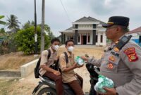 Kapolsek Buay Madang Timur Iptu Swisspo, menyerahkan paket makanan kepada sejumlah pelajar sekolah yang melintas di Desa Sumber Asri, Kecamatan Buay Madang Timur, Kabupaten OKU Timur.
