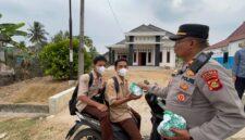 Kapolsek Buay Madang Timur Iptu Swisspo, menyerahkan paket makanan kepada sejumlah pelajar sekolah yang melintas di Desa Sumber Asri, Kecamatan Buay Madang Timur, Kabupaten OKU Timur.
