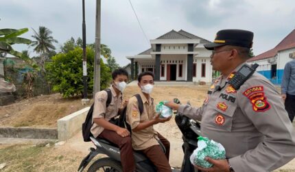 Kapolsek Buay Madang Timur Iptu Swisspo, menyerahkan paket makanan kepada sejumlah pelajar sekolah yang melintas di Desa Sumber Asri, Kecamatan Buay Madang Timur, Kabupaten OKU Timur.