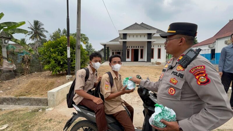 Kapolsek Buay Madang Timur Iptu Swisspo, menyerahkan paket makanan kepada sejumlah pelajar sekolah yang melintas di Desa Sumber Asri, Kecamatan Buay Madang Timur, Kabupaten OKU Timur.