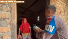 Personel Polsek Buay Madang Timur, Bripka Didi Handoko, menyerahkan paket makanan bantuan kepada seorang ibu rumah tangga di Desa Kedung Rejo, Kecamatan Buay Madang Timur, Kabupaten OKU Timur, Sumatera Selatan.