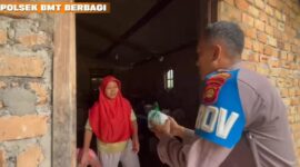 Personel Polsek Buay Madang Timur, Bripka Didi Handoko, menyerahkan paket makanan bantuan kepada seorang ibu rumah tangga di Desa Kedung Rejo, Kecamatan Buay Madang Timur, Kabupaten OKU Timur, Sumatera Selatan.
