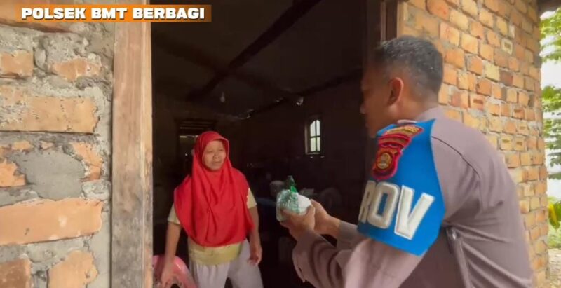 Personel Polsek Buay Madang Timur, Bripka Didi Handoko, menyerahkan paket makanan bantuan kepada seorang ibu rumah tangga di Desa Kedung Rejo, Kecamatan Buay Madang Timur, Kabupaten OKU Timur, Sumatera Selatan.