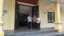 Personel Polsek Buay Madang Timur bersama pengurus gereja melakukan penjagaan di depan pintu masuk Gereja Trinitas Bangun Sari BK 3, Kecamatan Buay Madang Timur, Kabupaten OKU Timur.