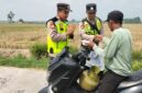 Ka Jaga Piket Polsek Buay Madang Timur Aipda Khoirul Alkaf menyerahkan paket makanan siap saji kepada seorang warga yang mengendarai sepeda motor di wilayah Kedu, Kecamatan Buay Madang Timur, Kabupaten OKU Timur.