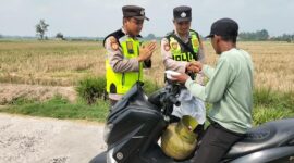 Ka Jaga Piket Polsek Buay Madang Timur Aipda Khoirul Alkaf menyerahkan paket makanan siap saji kepada seorang warga yang mengendarai sepeda motor di wilayah Kedu, Kecamatan Buay Madang Timur, Kabupaten OKU Timur.