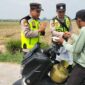 Ka Jaga Piket Polsek Buay Madang Timur Aipda Khoirul Alkaf menyerahkan paket makanan siap saji kepada seorang warga yang mengendarai sepeda motor di wilayah Kedu, Kecamatan Buay Madang Timur, Kabupaten OKU Timur.