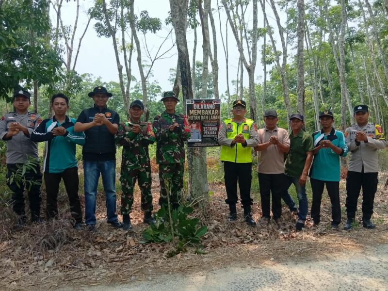 Kapolsek Buay Madang Timur Iptu Swisspo, bersama personel TNI, staf kecamatan, dan perangkat desa berfoto bersama usai memasang spanduk imbauan larangan membakar hutan dan lahan di Desa Teko Rejo, Kecamatan Buay Madang Timur, Kabupaten OKU Timur.