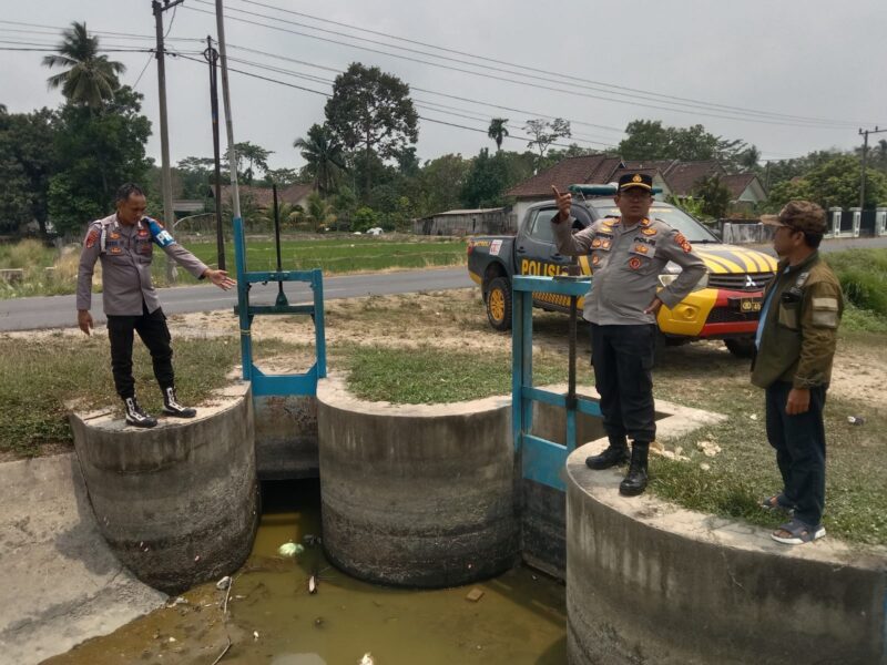 Kapolsek Buay Madang Timur Iptu Swisspo, didampingi Ps Kanit Provost Bripka Didi Handoko dan Ketua BPD Desa Sumber Harjo Yudi Panjalu, meninjau langsung kondisi pintu air saluran irigasi di Kecamatan Buay Madang Timur, OKU Timur.