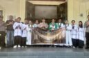 Kapolsek Buay Madang Timur Iptu Swisspo, didampingi personel Polsek, Romo Emilianus SCJ, dan pengurus gereja membentangkan spanduk program 