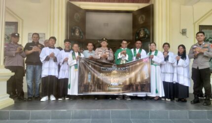 Kapolsek Buay Madang Timur Iptu Swisspo, didampingi personel Polsek, Romo Emilianus SCJ, dan pengurus gereja membentangkan spanduk program "Minggu Kasih" di depan pintu utama Gereja Trinitas Bangun Sari, Kecamatan Buay Madang Timur, Kabupaten OKU Timur, Sumatera Selatan.
